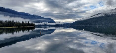 The reflection of this landscape creates an almost perfect symmetry in the photo taken on a misty winter morning at Main Beach, Cultus Lake, BC.